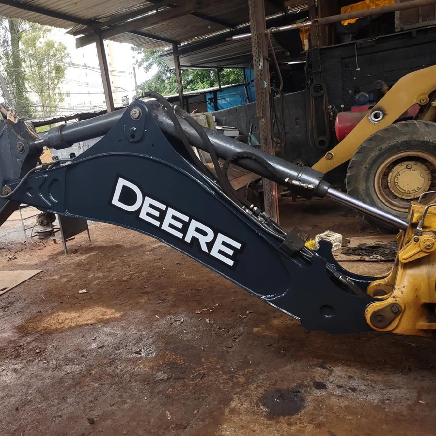 Lança de retroescavadeira John Deere recuperada depois de quebrar, montada na máquina, no galpão da oficina