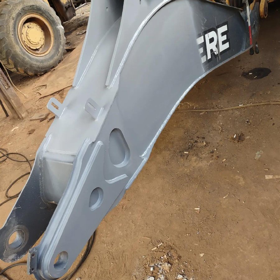 Lança de retroescavadeira John Deere recuperada e pintada de cinza, no chão da oficina